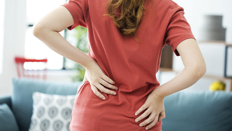 Woman suffering from back pain in need of a Ponderay Chiropractor at By Design Chiropractic