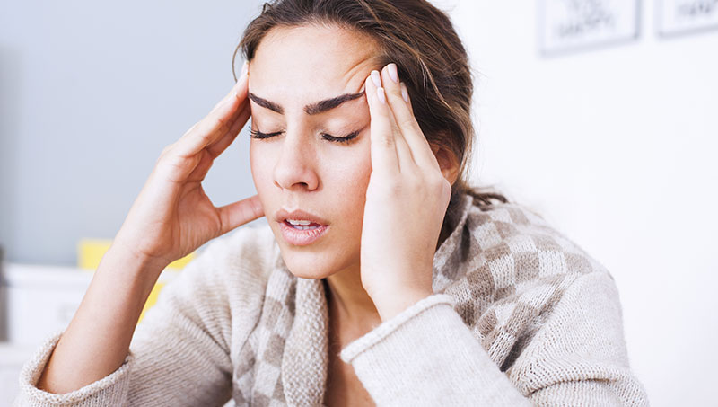 Woman suffering from a headache in need of a Ponderay Chiropractor at By Design Chiropractic